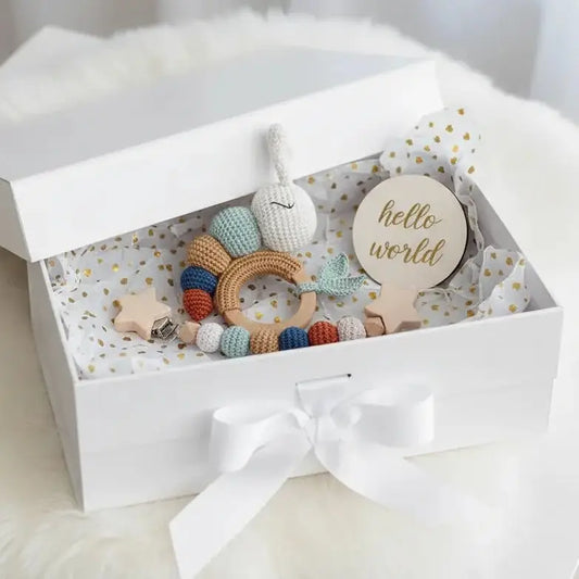 Handmade crochet baby toys and "hello world" tag in a white gift box with bow