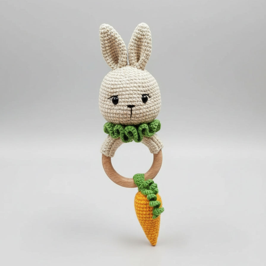 Crocheted bunny rattle with wooden ring and carrot-shaped toy, held by hand