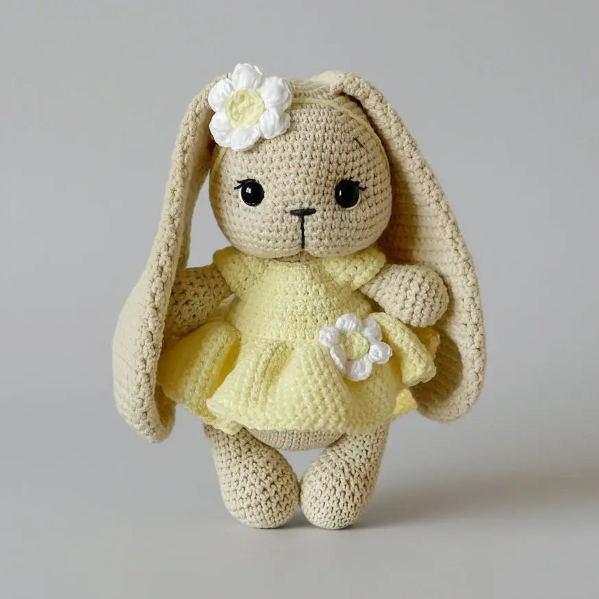 Crocheted bunny wearing a yellow dress with white flower decorations
