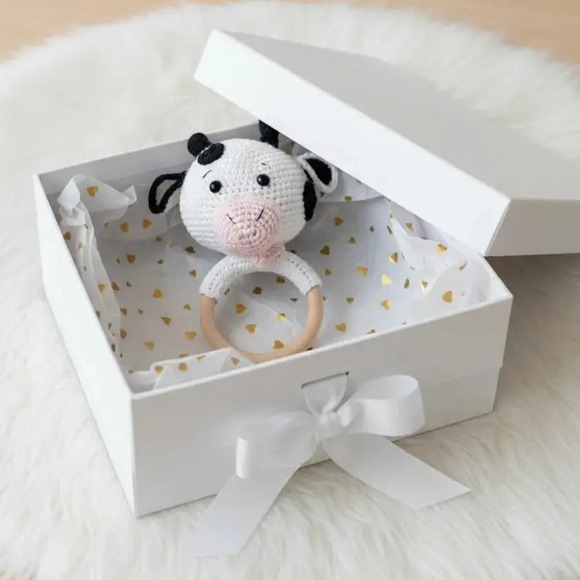 Crocheted cow rattle in white gift box with gold hearts and white ribbon