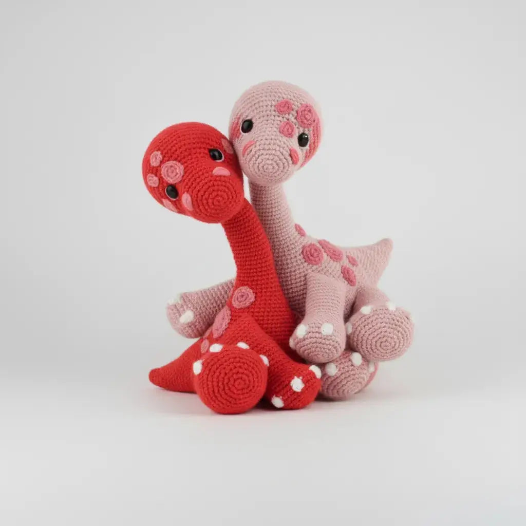 Two crocheted dinosaurs in red and pink, with polka dot details and curved necks.