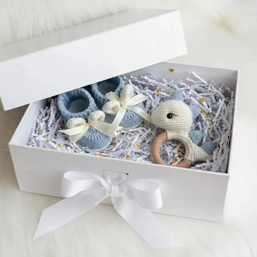 Blue crocheted baby booties and stuffed animal in a gift box with white ribbon