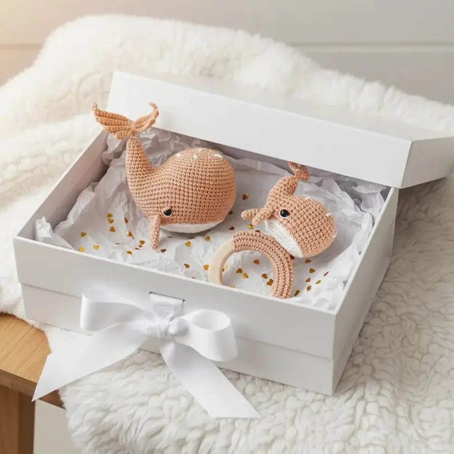 Crocheted whale and fox baby toys nestled in a gift box with white ribbon