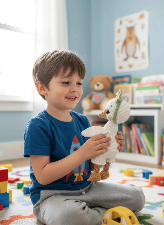 Smiling boy playing with crocheted stuffed animal in colorful playroom with toys and books.