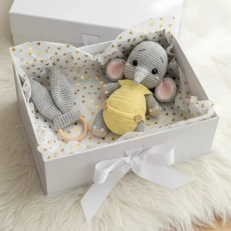 Crocheted gray elephant and teething ring in a gift box with gold heart pattern
