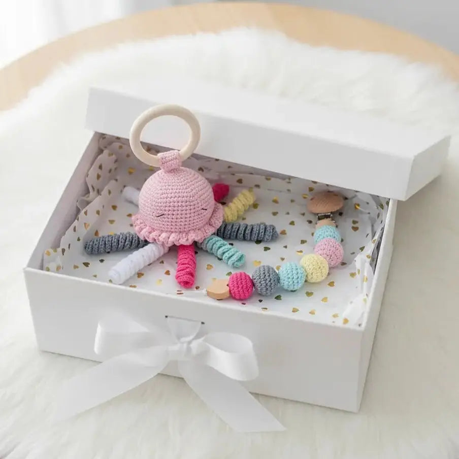 Crocheted pink octopus and colorful beads in a white gift box with gold hearts
