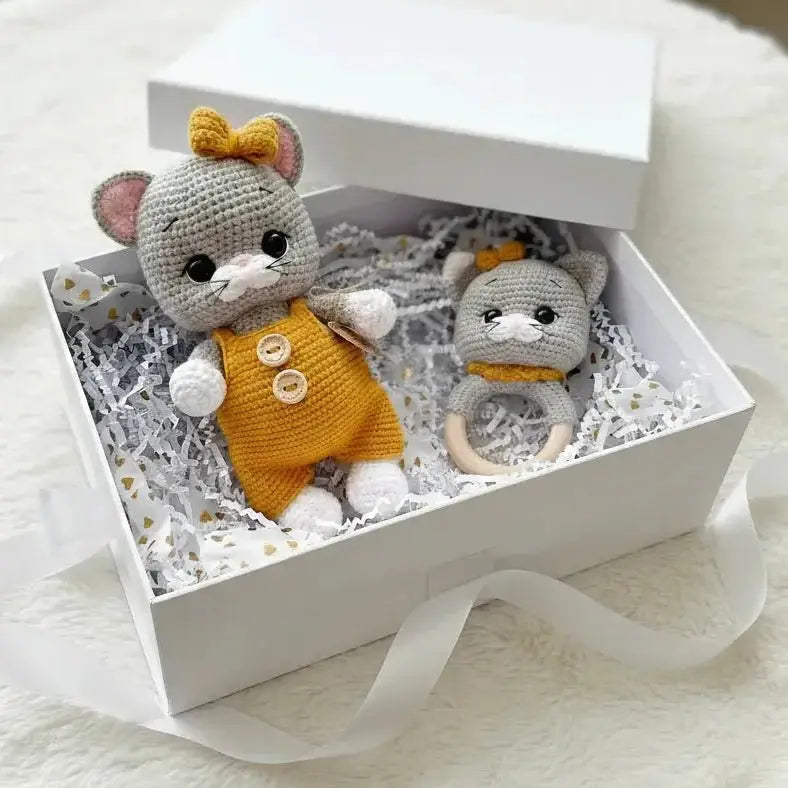 Crocheted gray mouse toys in yellow outfits nestled in a white gift box with ribbon