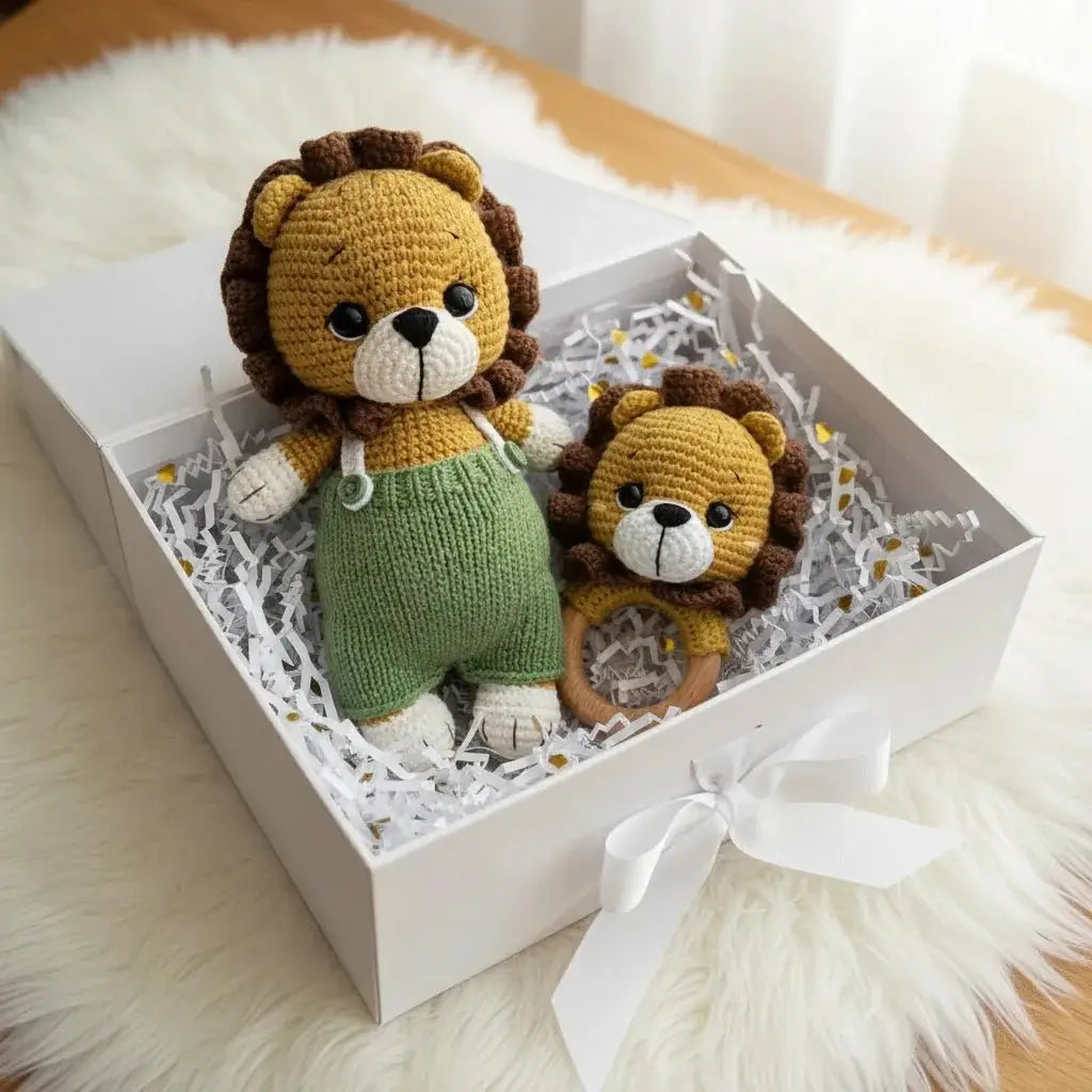 Two crocheted lion stuffed animals in a white gift box with white ribbon, sitting on fluffy white surface