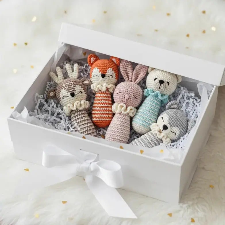 Crocheted woodland animal rattles nestled in a white gift box with ribbon
