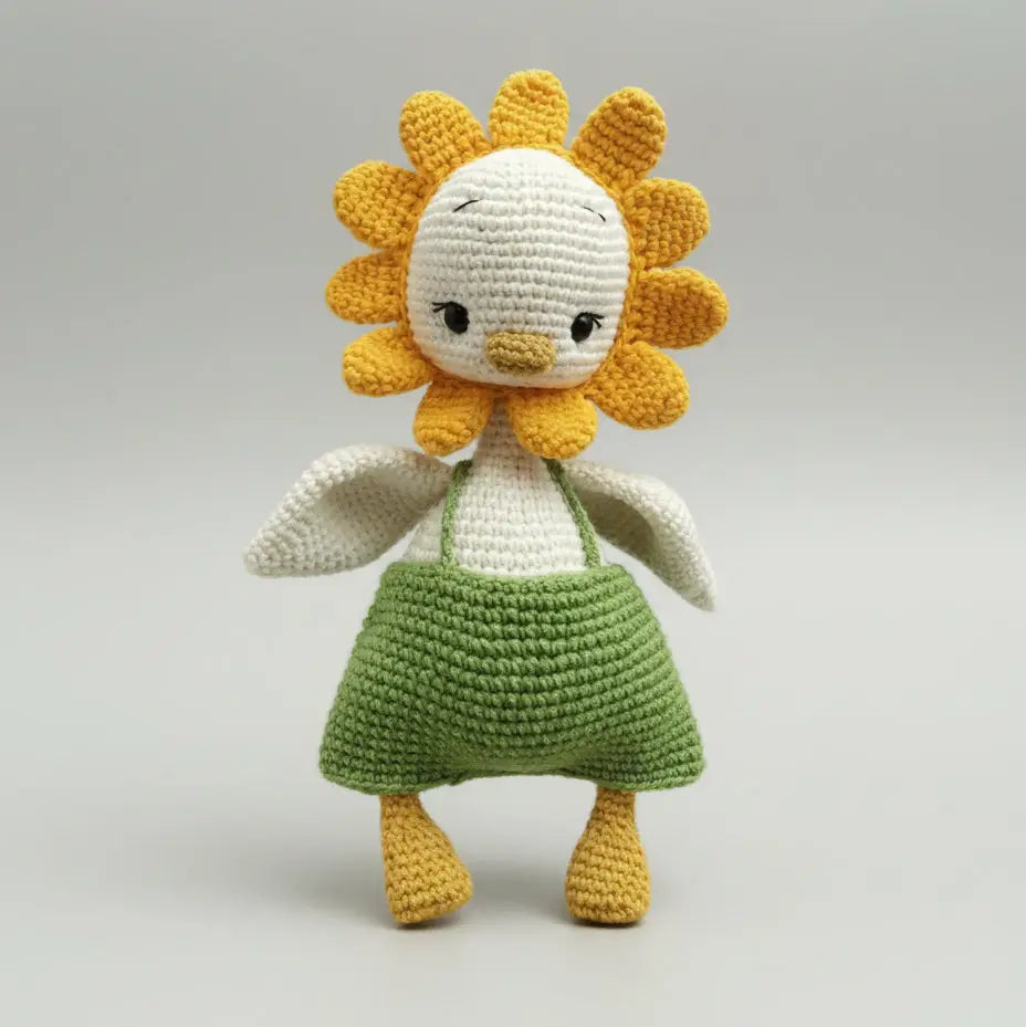 Crocheted sunflower doll with white body, yellow petals, and green skirt on gray background