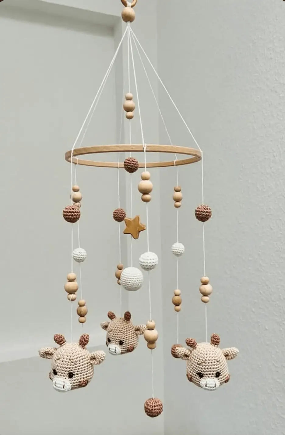 Crocheted baby mobile with deer, wooden beads, white spheres, and a golden star