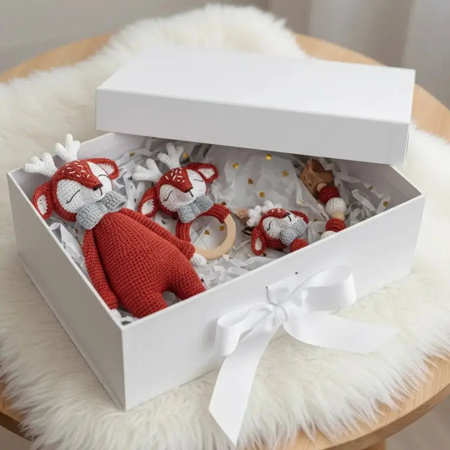 Crocheted red and white fox dolls nestled in a gift box with white ribbon