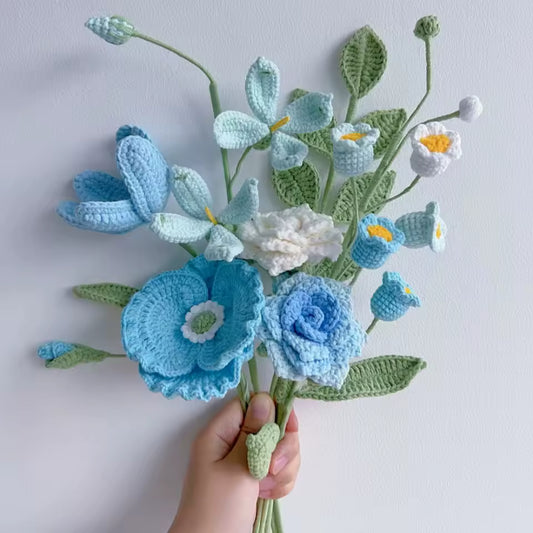 Crocheted blue and white flower bouquet held by a hand against a light background
