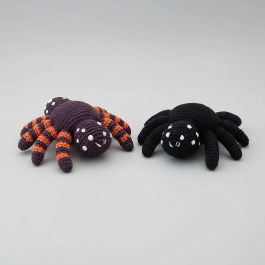 Two crocheted spiders - one purple and orange, one black - with white dot eyes