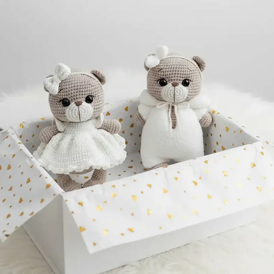 Two crocheted teddy bears in a decorative box with a white and gold polka dot interior.