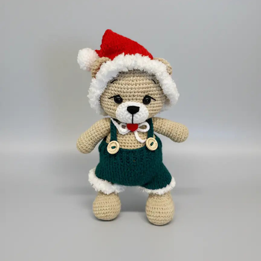 Crocheted teddy bear in Christmas outfit with red hat and green dress
