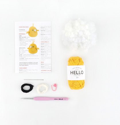 Yellow yarn, crochet hook, pattern, and supplies for a crafting project on white background