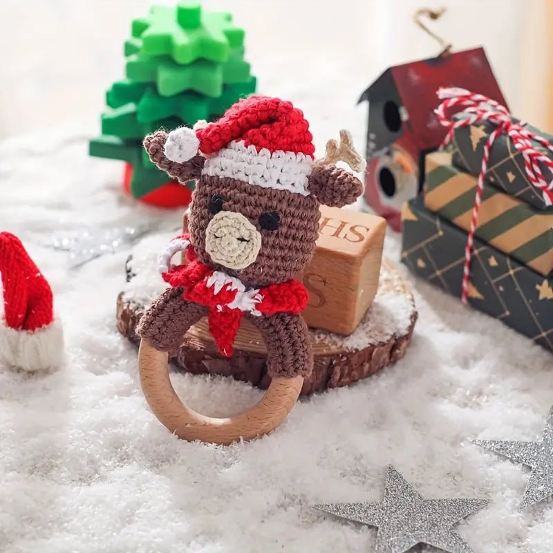 Crocheted reindeer in Santa hat on wooden ring, surrounded by Christmas decorations and snow