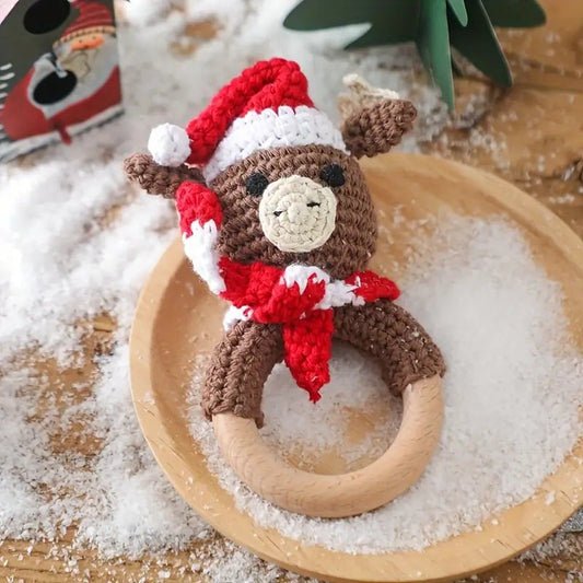 Crocheted reindeer in Santa hat sitting on wooden ring, surrounded by fake snow