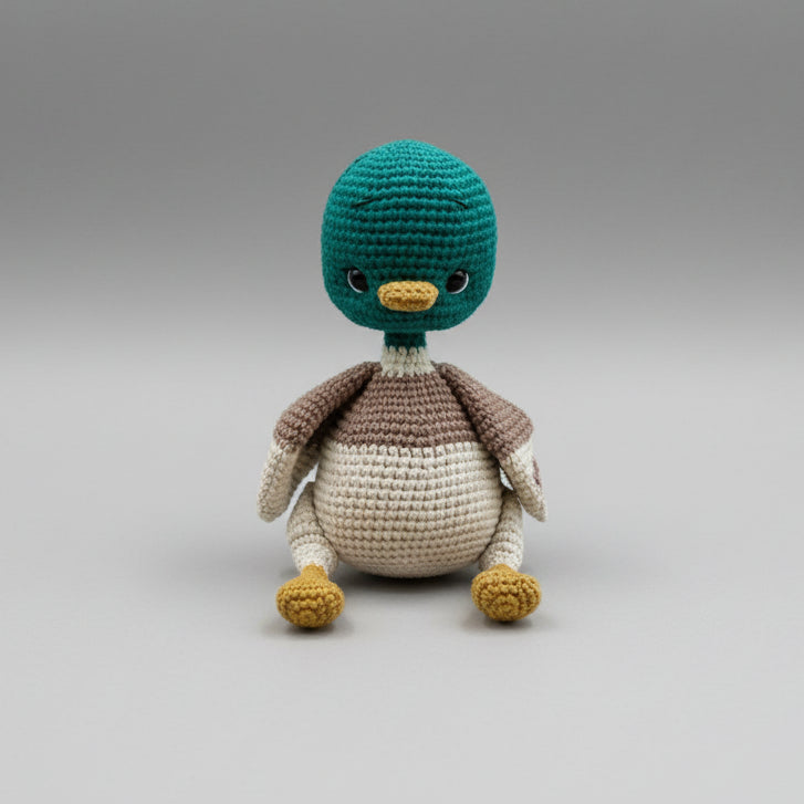 Crocheted teal and brown penguin stuffed animal with yellow beak and feet