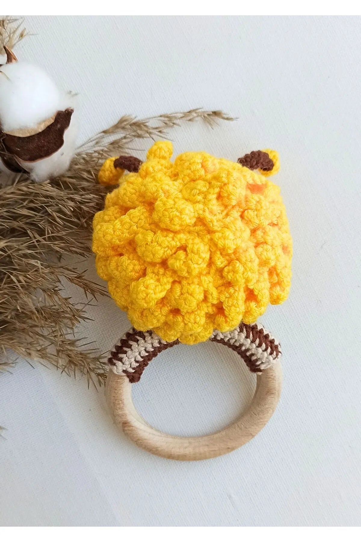 Crocheted yellow chick teething ring with brown striped legs on wooden circle