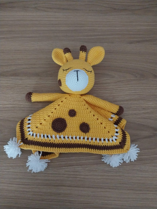 Crocheted yellow giraffe lovey blanket with brown spots and white pom-poms