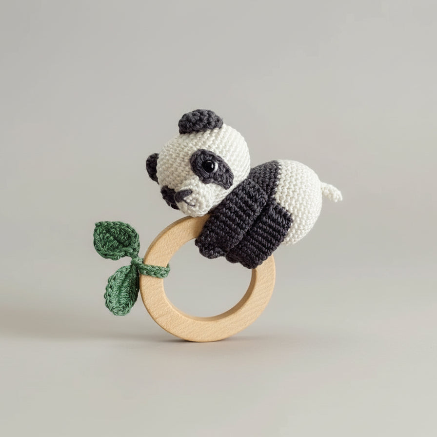 Crocheted panda baby rattle with wooden teething ring and green leaf detail
