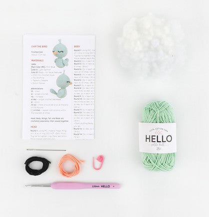 Knitting supplies: mint green yarn, pattern, crochet hook, and colored elastic bands