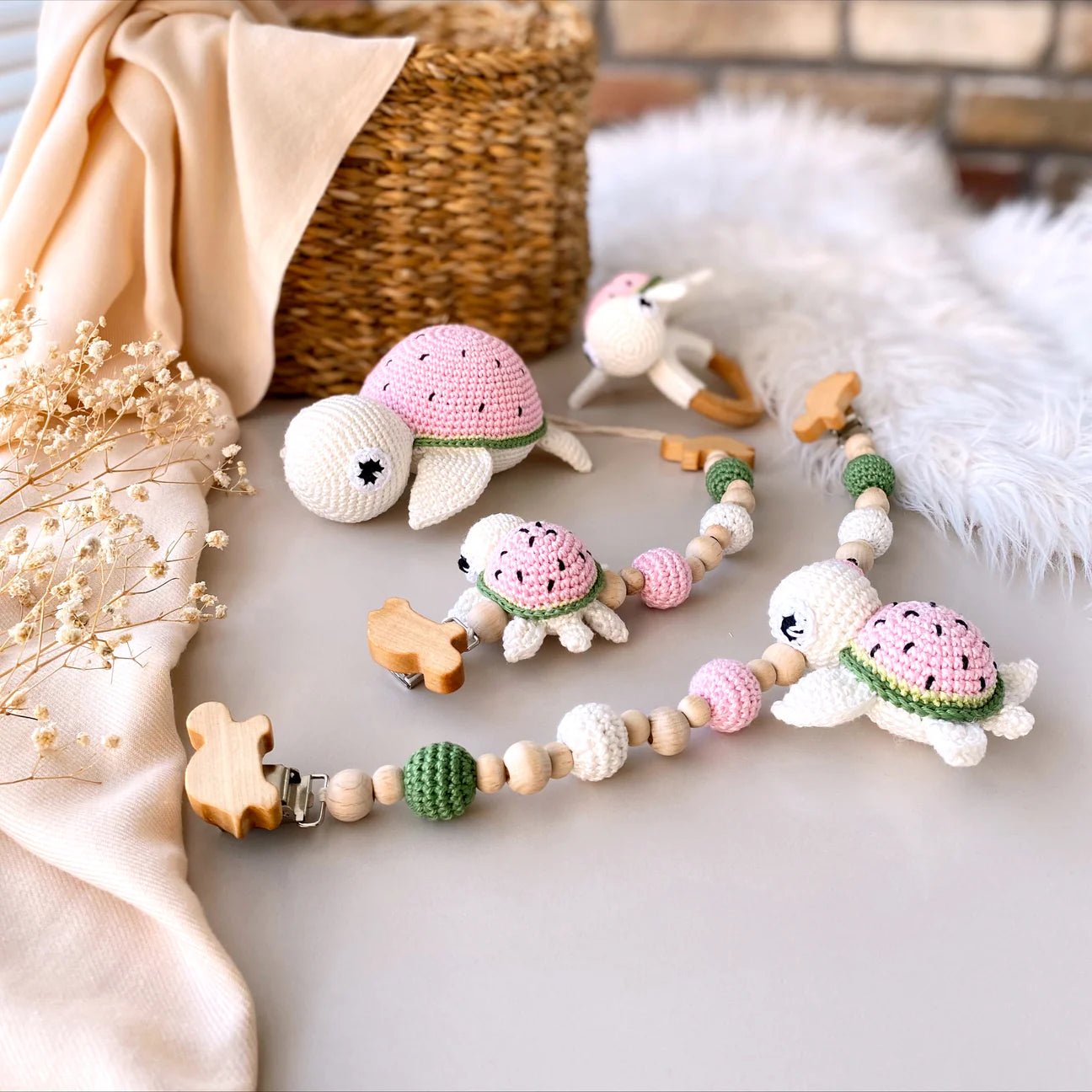 Crocheted pink and white turtle toys with wooden beads on a soft, textured background
