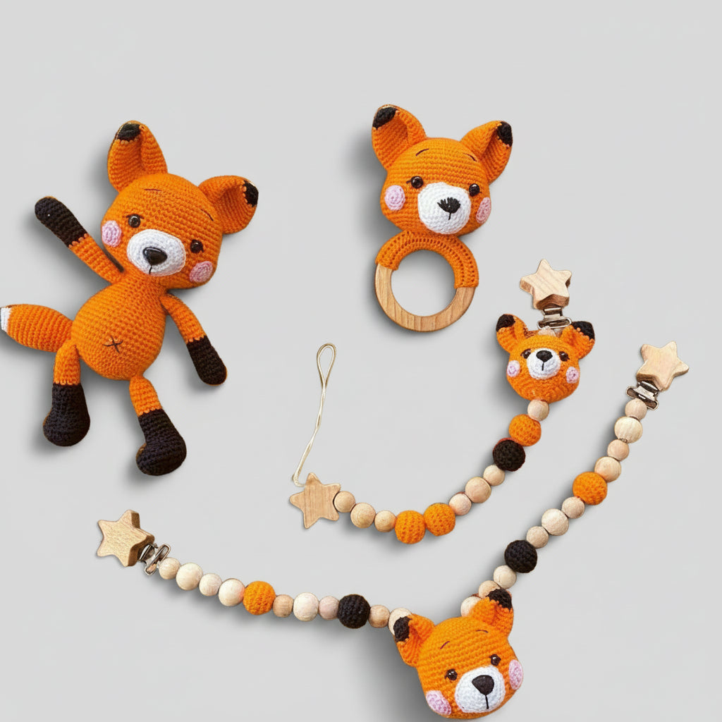 Handmade orange crocheted fox toys: soft plush, wooden teething ring, and star-adorned pacifier clip