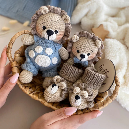 Crocheted lion stuffed animals in blue and beige, nestled in a woven basket with "hello" tag