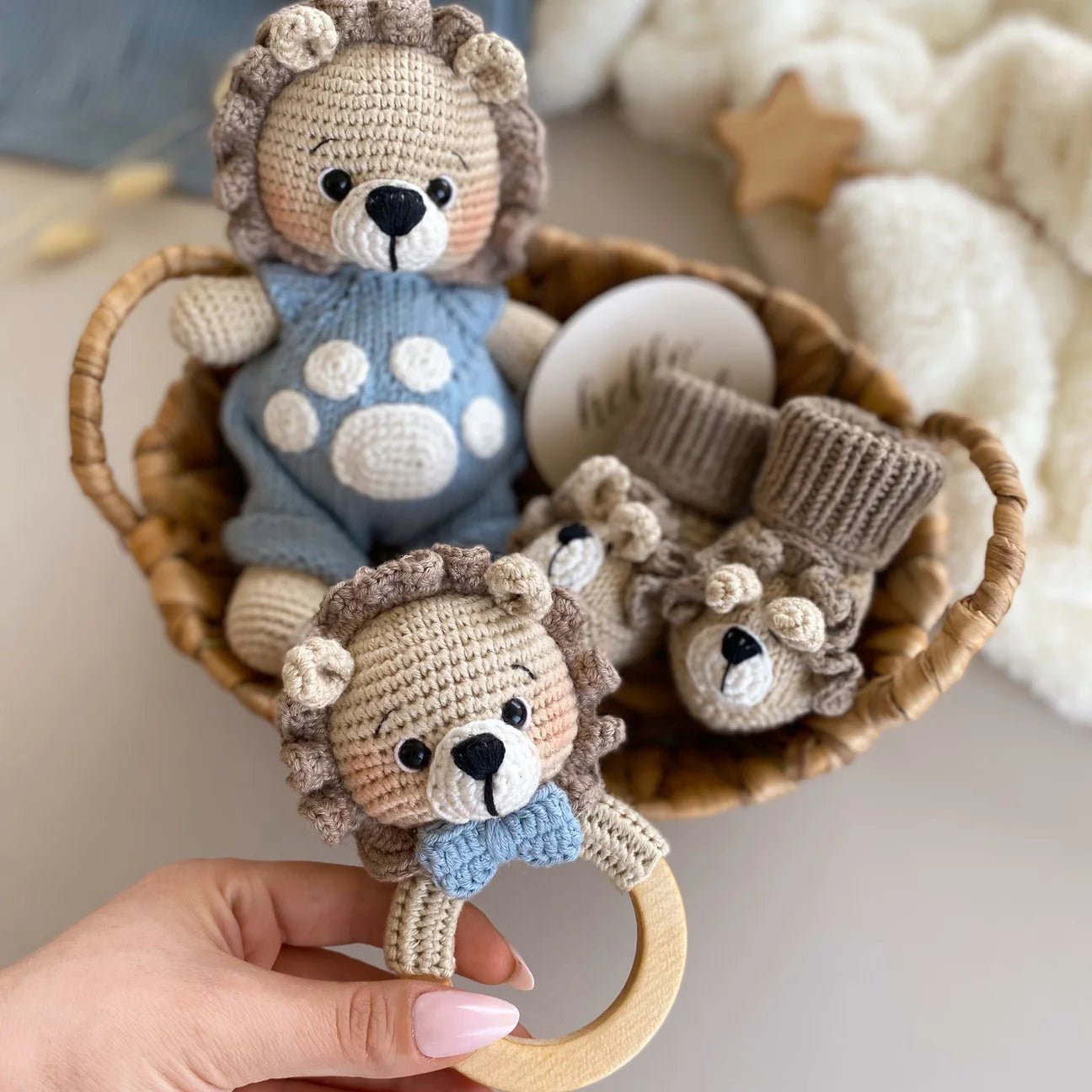Crocheted lion baby rattle and booties in a woven basket, with wooden teething ring