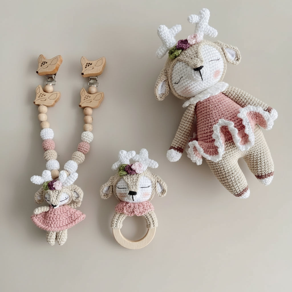 Crocheted deer-themed baby accessories: pacifier clips, rattle, and stuffed toy in pink and beige