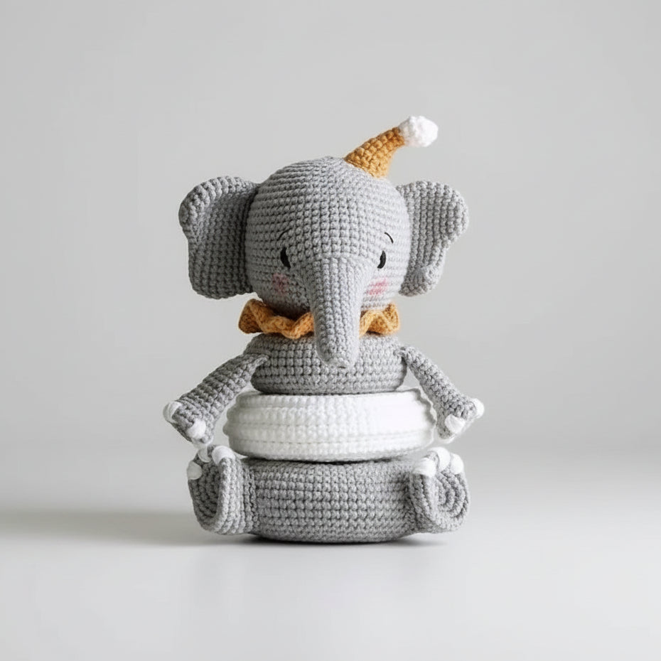 Crocheted gray elephant with yellow hat and bow, sitting in someone's hand