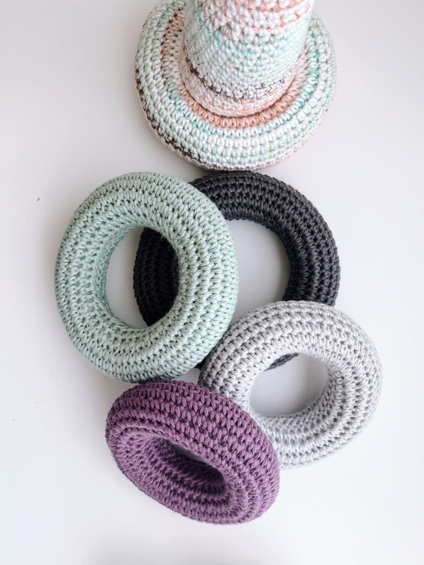 Crocheted rings in pastel colors: mint green, gray, white, purple, and soft peach