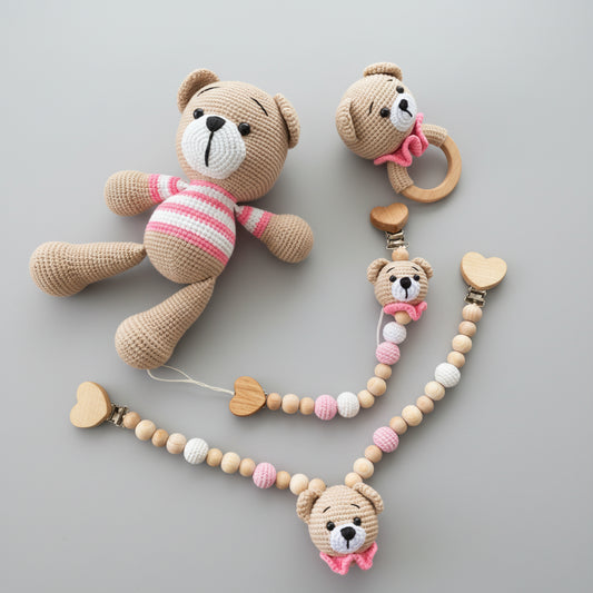 Crocheted teddy bears with pink accents and wooden beaded accessories on wooden background
