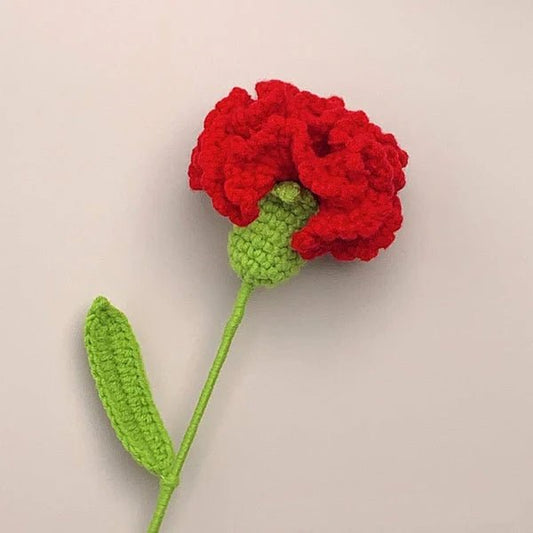 Crocheted red carnation flower with green stem against neutral background