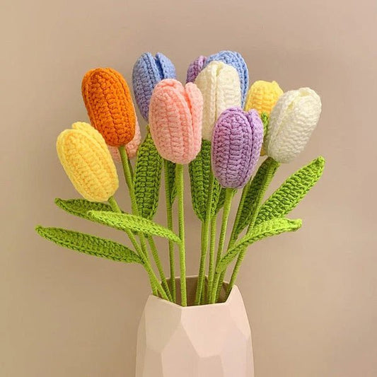 Crocheted tulips in pastel colors with green stems, arranged in a white geometric vase.
