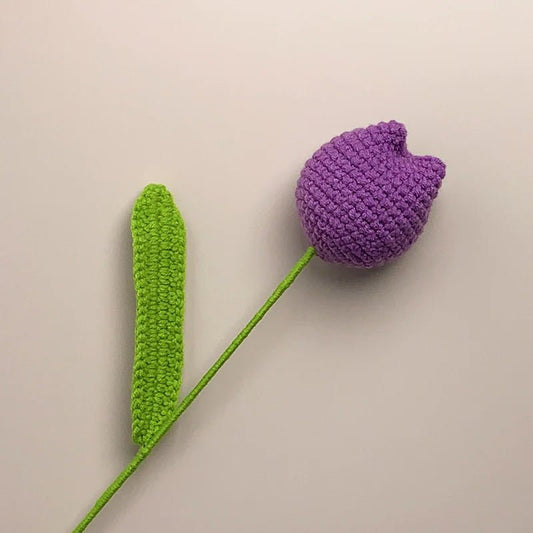 Crocheted purple tulip with green stem on neutral background