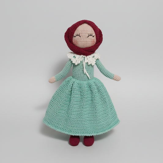 Crocheted doll in mint green dress with red bonnet and white ruffled collar