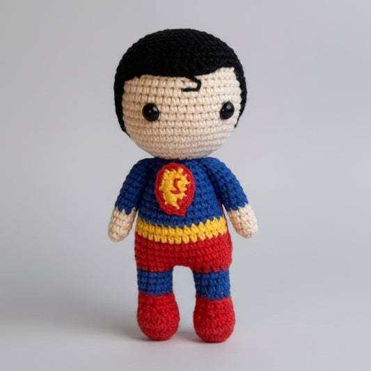 Crocheted superhero doll with blue, yellow, and red costume standing on a log in forest