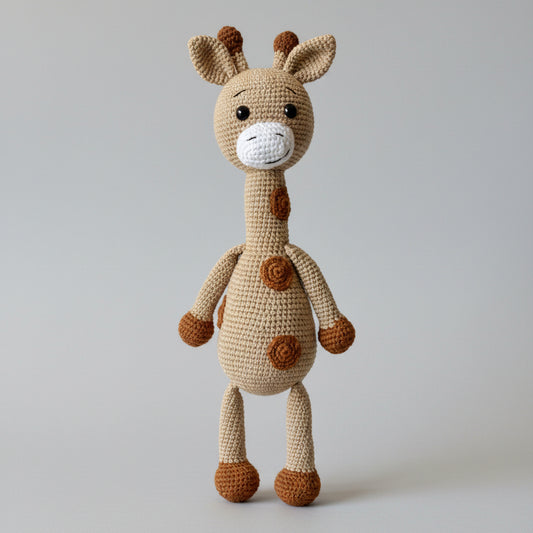 Crocheted giraffe stuffed animal in beige and brown, with long neck and spotted body, standing against a gray background.