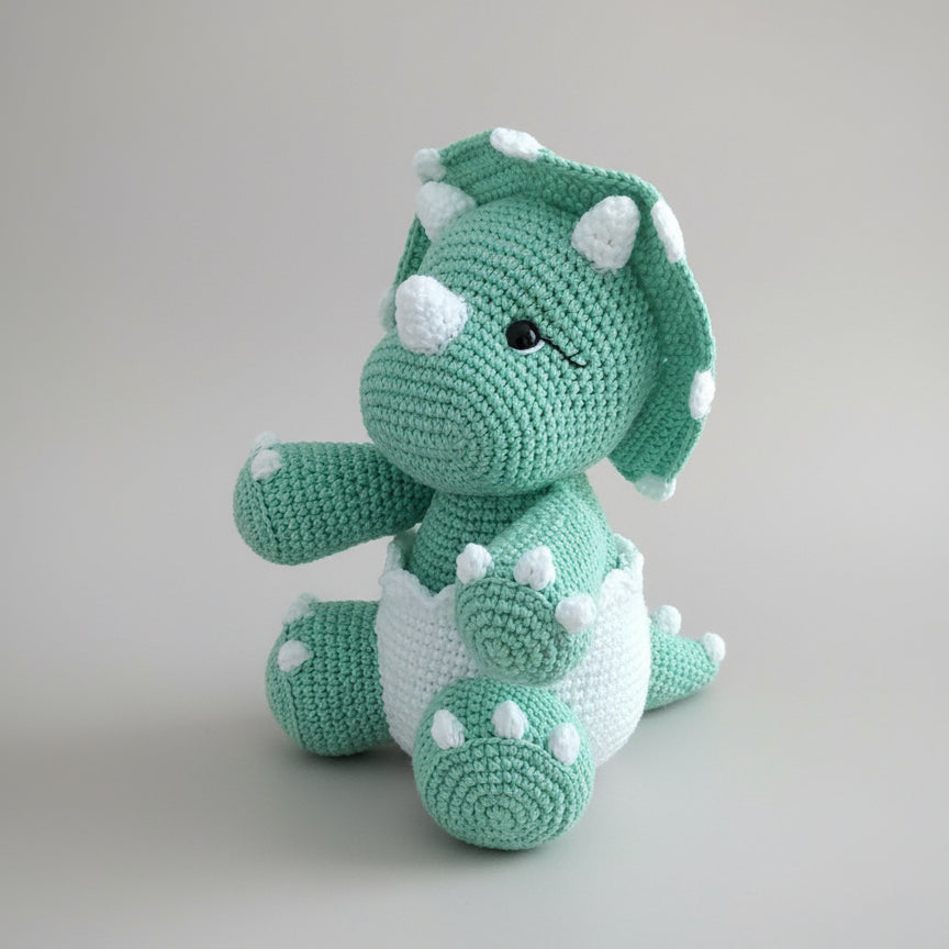 Crocheted green and white triceratops stuffed animal with white bumps