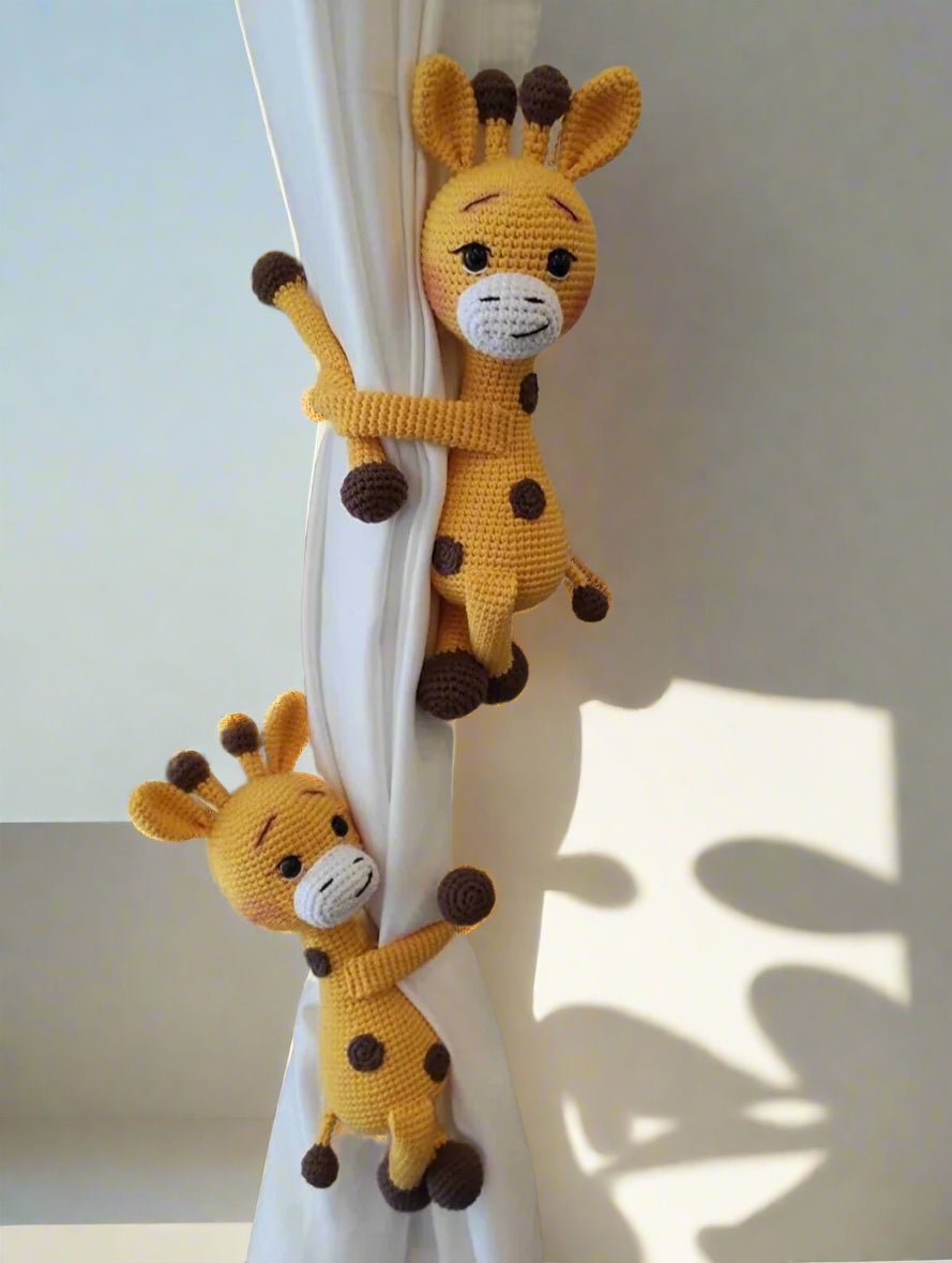 Two crocheted yellow giraffes hugging a white curtain, with playful shadows behind them