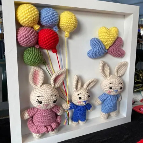 a group of crocheted rabbits holding balloons