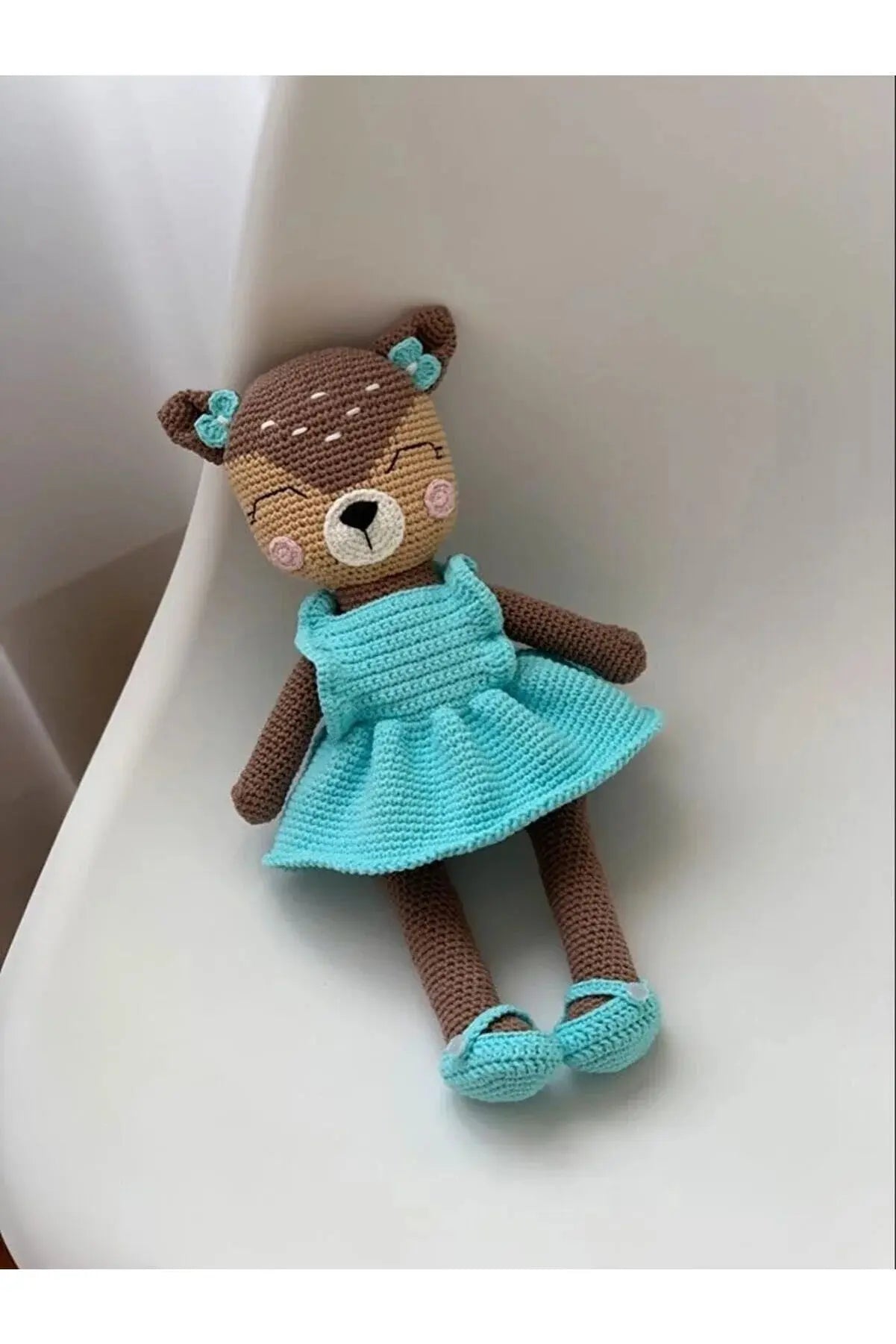 a crocheted teddy bear in a blue dress