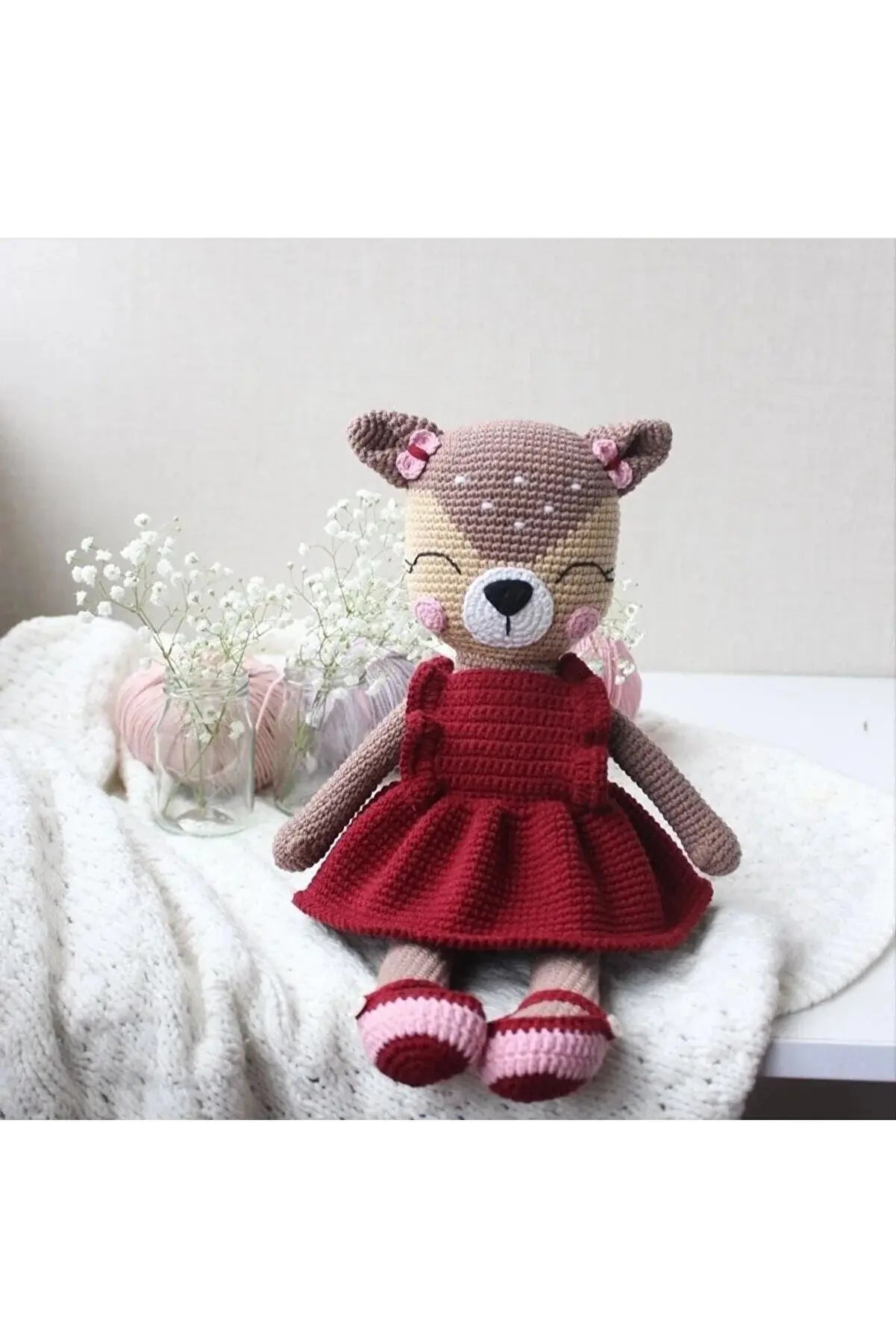 a teddy bear in a red dress sitting on a bed