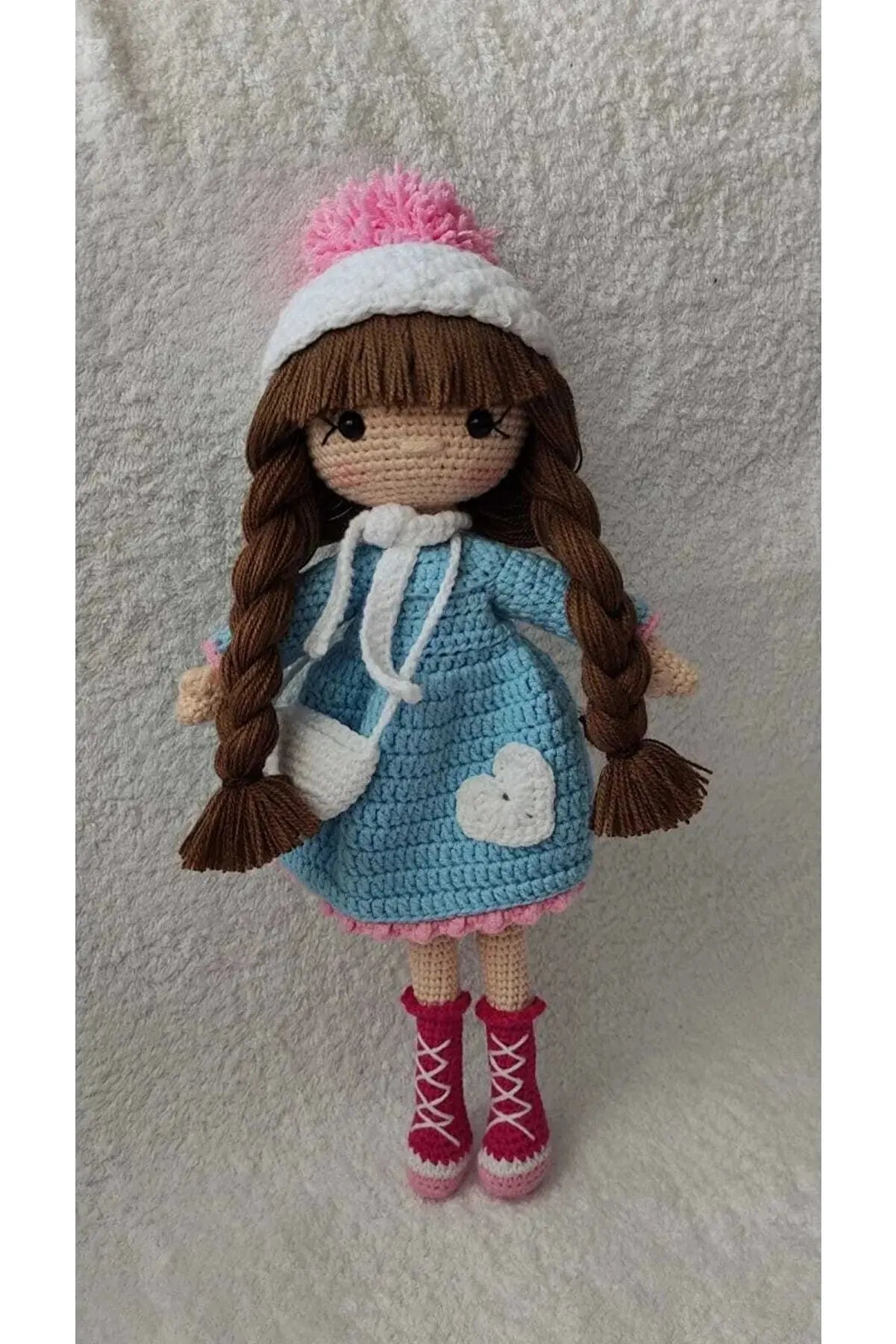 a crocheted doll wearing a blue dress and pink boots