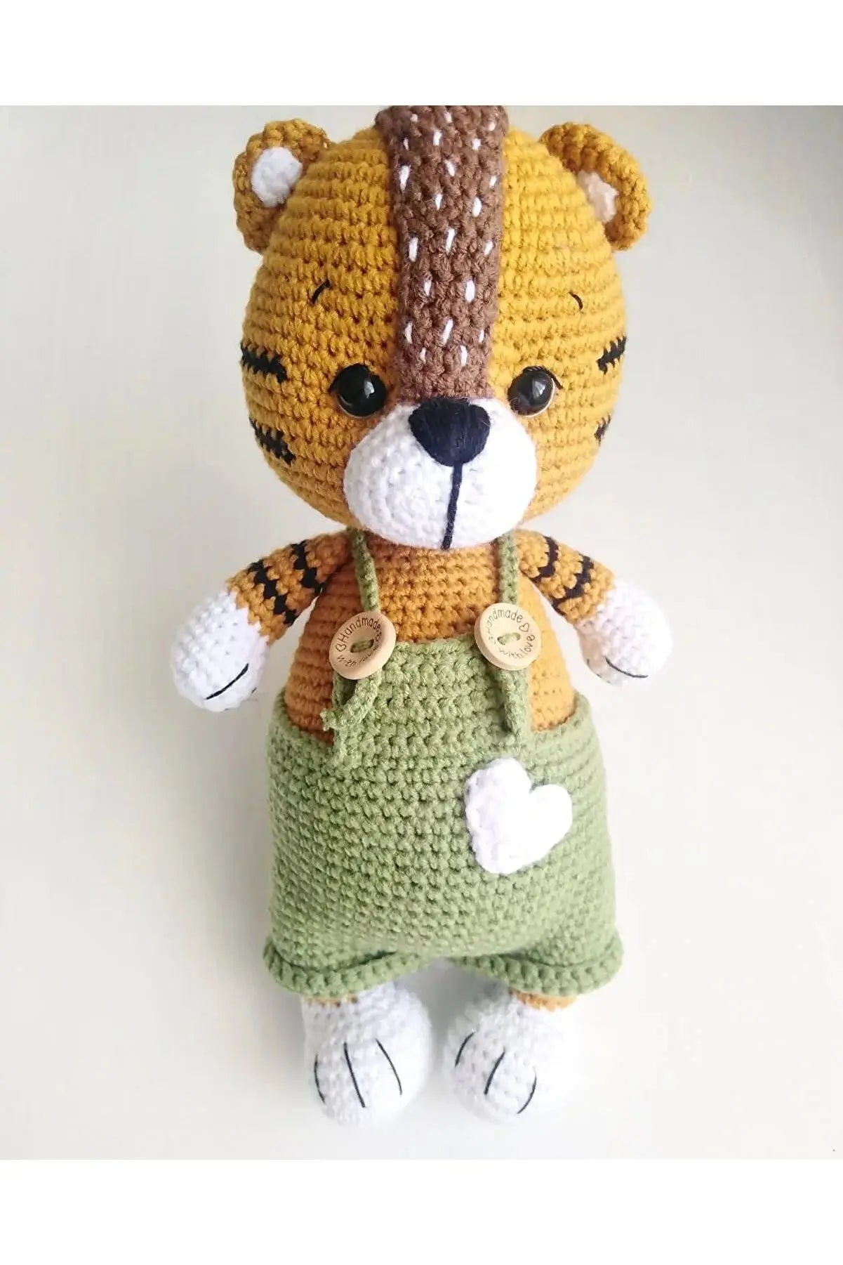 a crocheted teddy bear wearing a green dress