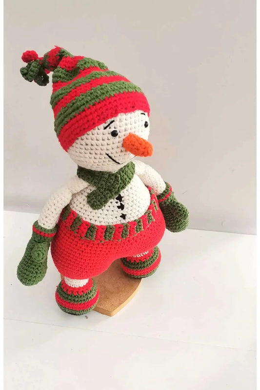 a crocheted snowman sitting on top of a wooden block